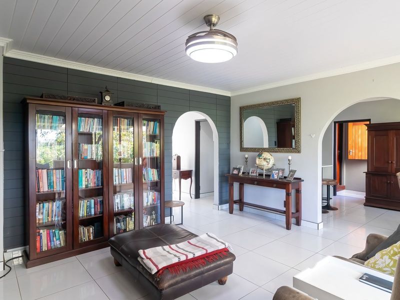 Spacious living area featuring tiled flooring, a distinctive tongue and groove ceiling, and elegant archways leading to adjacent rooms.