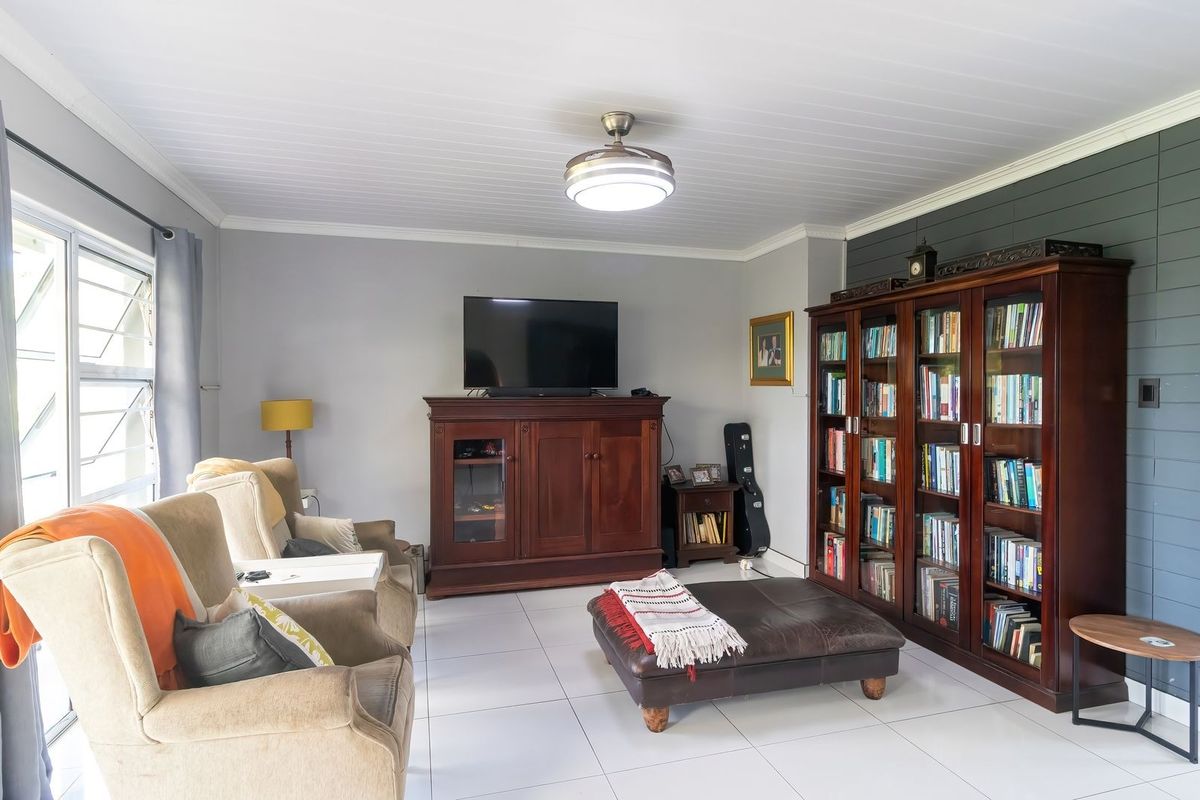 A well-maintained living room featuring tiled flooring, a tongue and groove ceiling, and a decorative accent wall with louver windows.