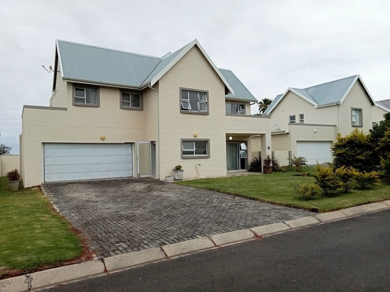 Front elevation of a double-storey cluster home featuring a paved driveway, double garage, and well-maintained garden.