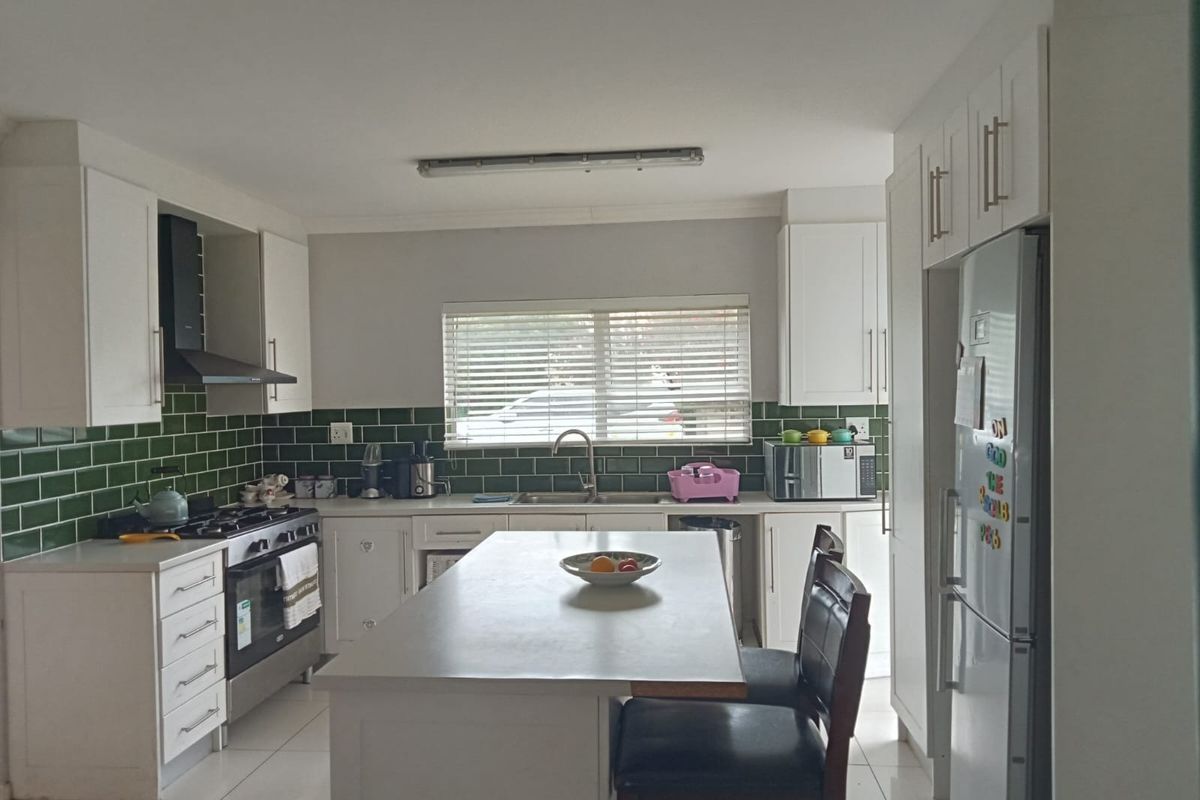 A functional kitchen featuring white cabinetry, a central island, green subway tile backsplash, and a gas stove with an extractor fan.