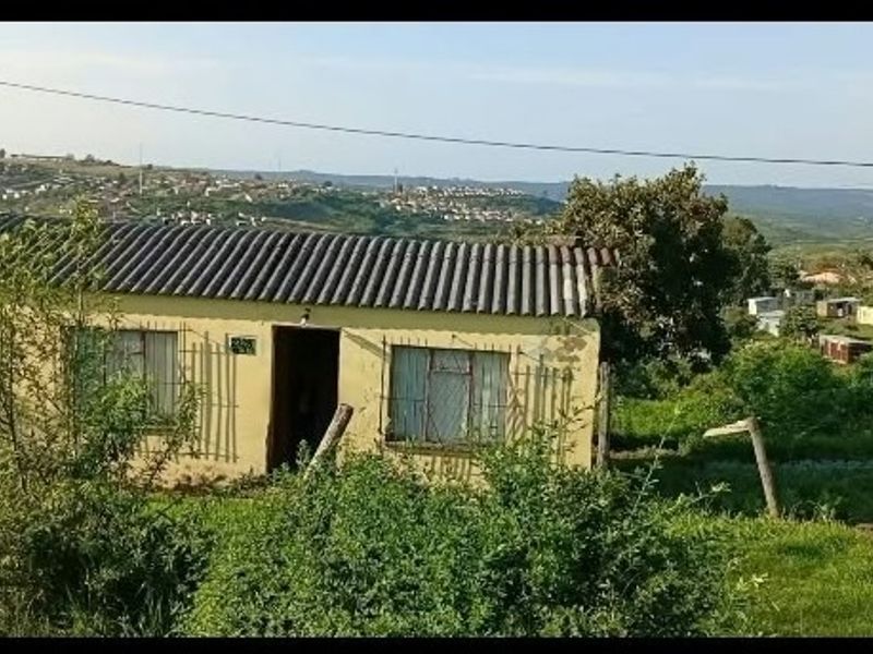 A single-story residential property featuring a corrugated roof and security bars on windows, situated in a hillside neighborhood setting.