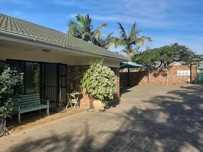 Front exterior view of the townhouse featuring a brick facade, tiled roof, and a spacious paved driveway with a secure entrance.