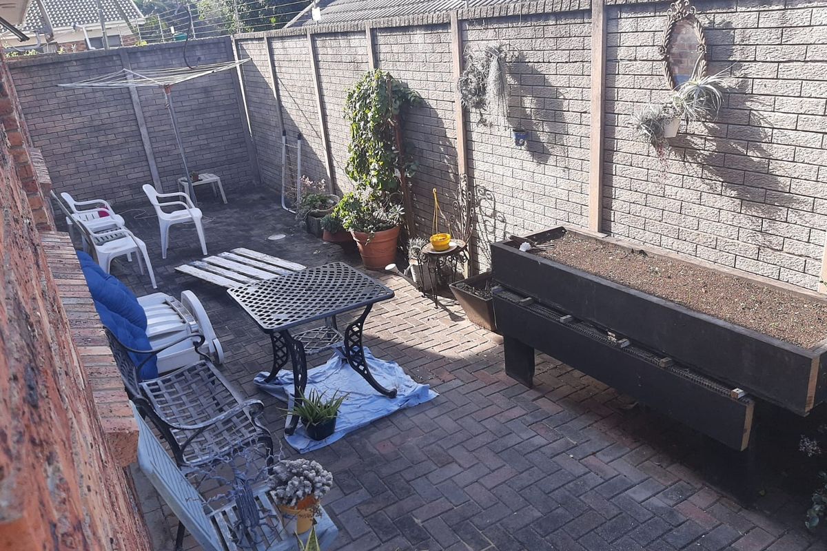 A private rear courtyard featuring paved flooring and high brick boundary walls with integrated electric fencing, offering a functional outdoor space.