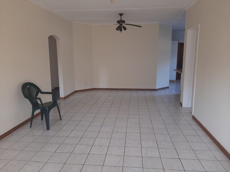 Spacious, empty living area featuring neutral walls, tiled flooring, and a ceiling fan, offering a blank canvas for interior design.