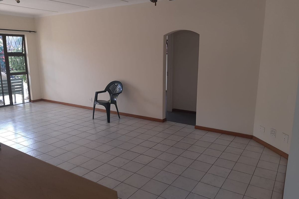 Spacious living area featuring tiled flooring, a ceiling fan, and an arched doorway leading to adjacent rooms, offering a blank canvas for interior design.