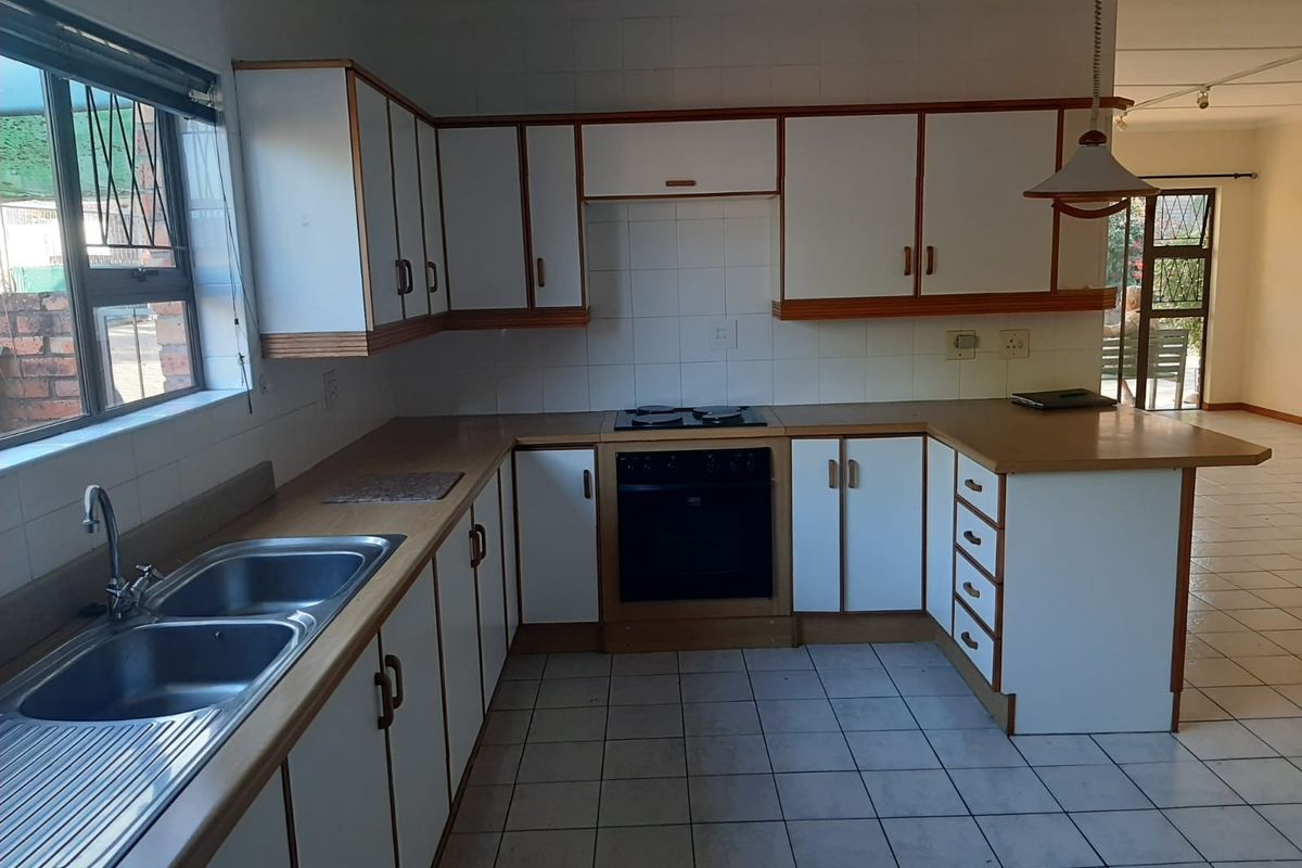 A functional kitchen featuring white cabinetry, laminate countertops, a built-in oven, and a double stainless steel sink with tiled flooring.