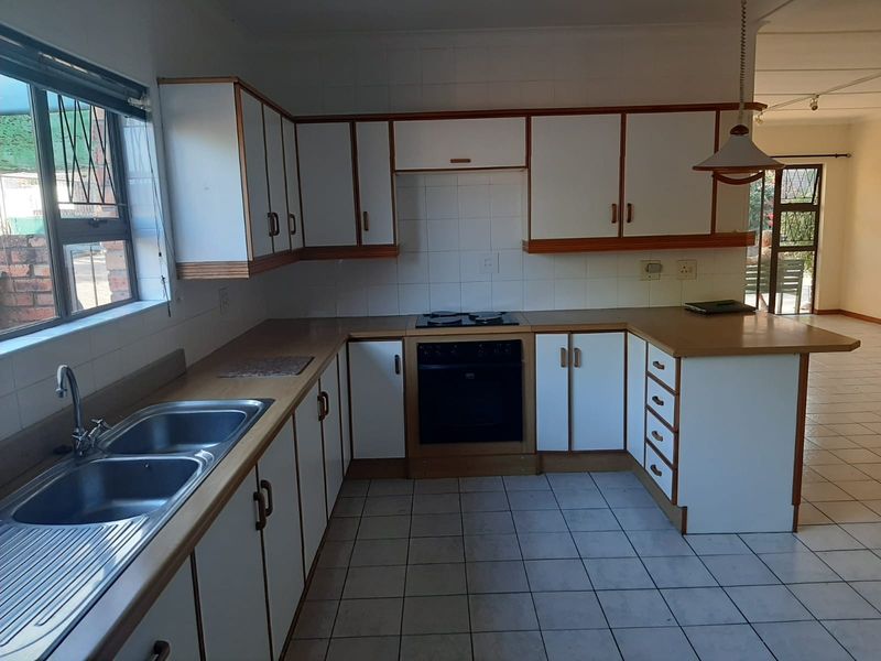 A functional kitchen featuring white cabinetry, laminate countertops, a built-in oven, and a double stainless steel sink with tiled flooring.