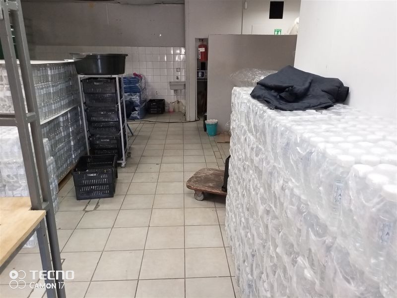 A functional utility or storage area featuring tiled flooring, a wall-mounted basin, and tiled splashbacks, currently used for bulk storage.