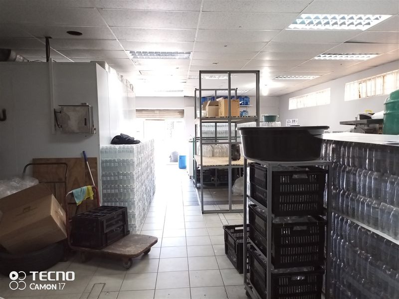 A functional utility or storage space featuring a suspended ceiling, fluorescent lighting, and tiled flooring, currently utilized for inventory storage.