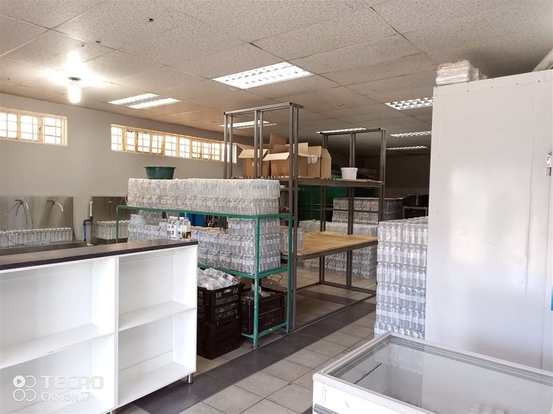 Functional utility or storage space featuring tiled flooring, suspended ceiling with integrated lighting, and industrial metal shelving units for inventory management.