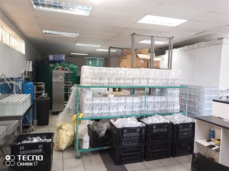 A functional utility or storage space featuring tiled flooring, suspended ceiling with integrated lighting, and industrial water filtration infrastructure.
