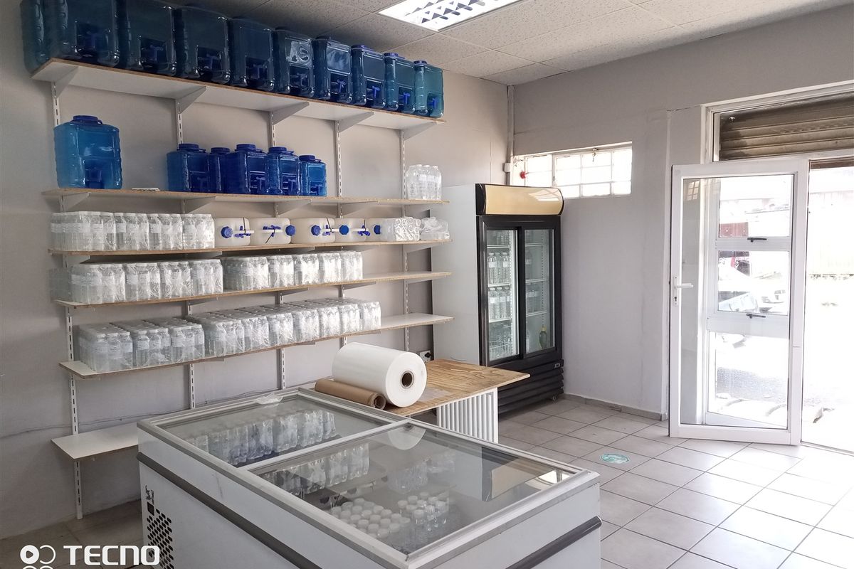 A functional retail utility or storage space featuring tiled flooring, wall-mounted shelving, and a glass entrance door.