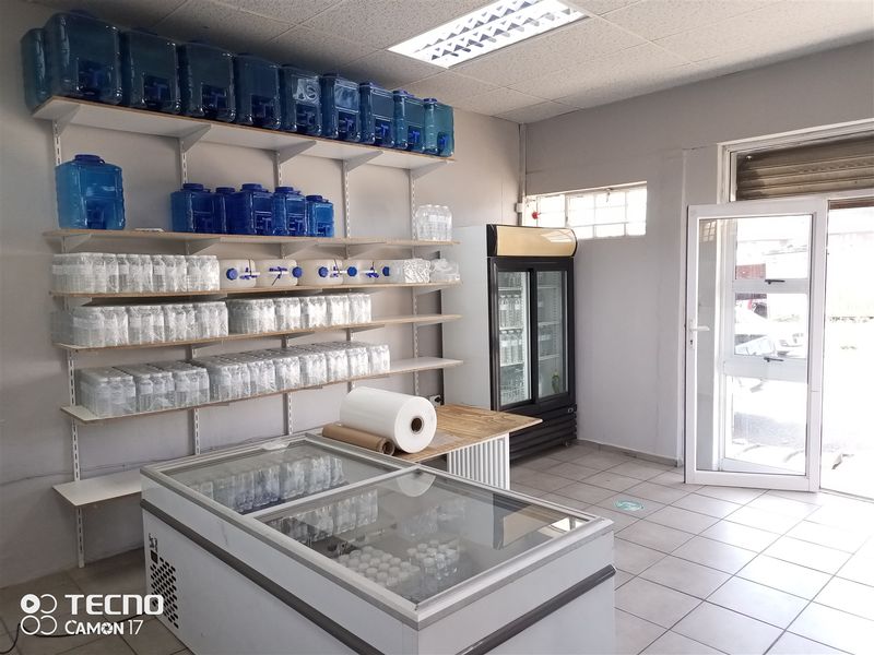 A functional retail utility or storage space featuring tiled flooring, wall-mounted shelving, and a glass entrance door.