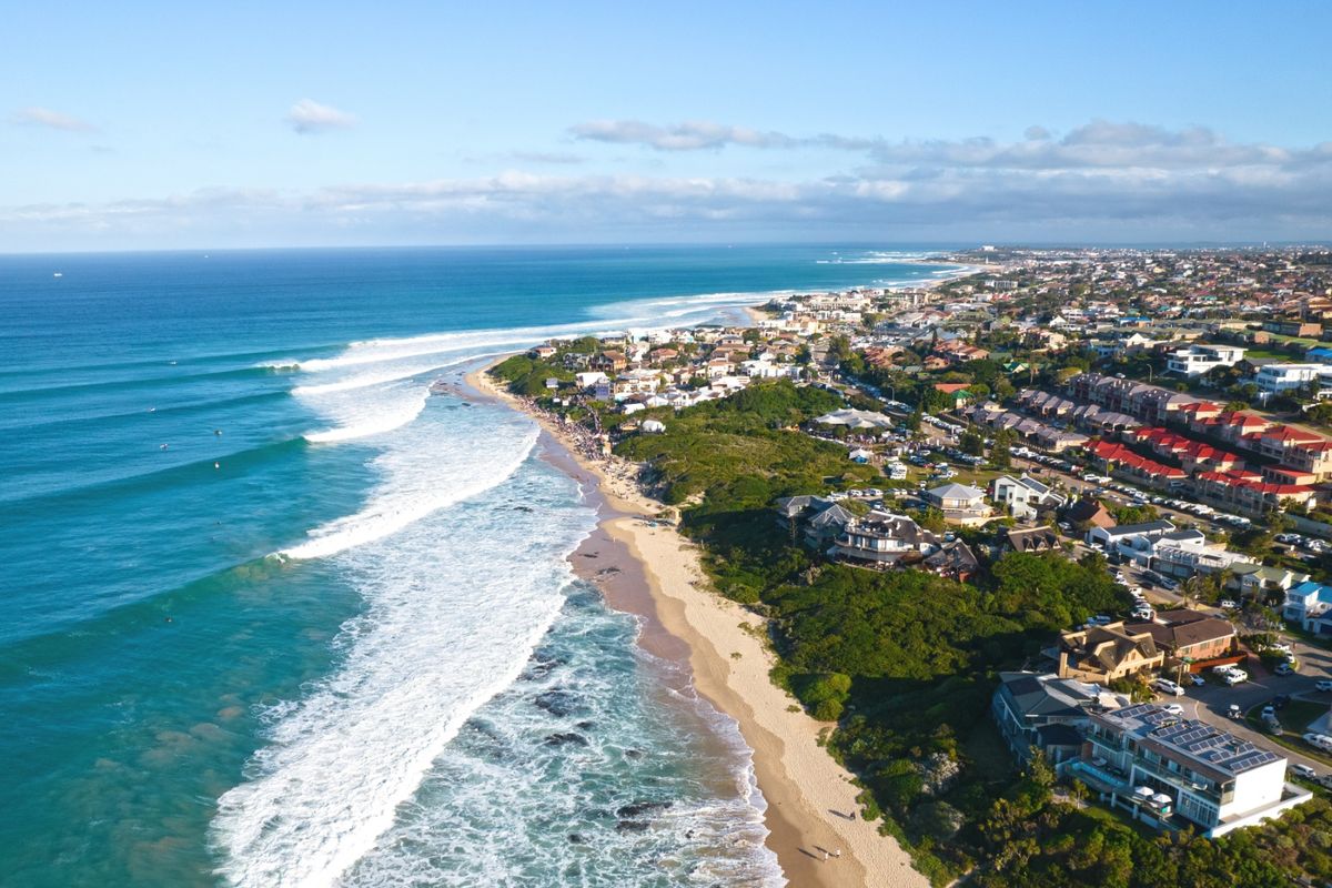 An aerial view of the coastal residential area, showcasing the beach, ocean, and surrounding neighborhood landscape.