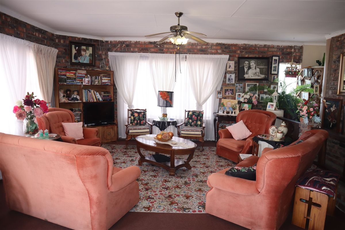 A cozy living room featuring exposed brick walls, a ceiling fan, and large windows that provide ample natural light.