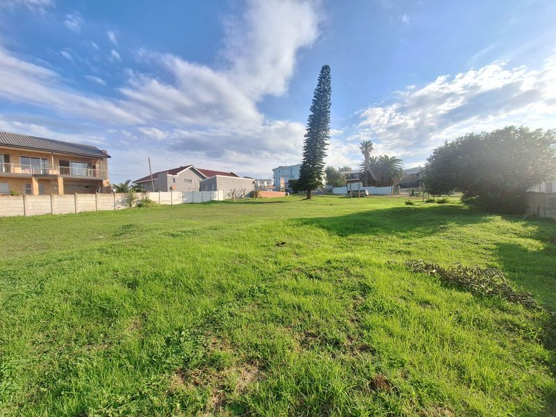 A spacious, level residential vacant plot featuring established grass cover and perimeter boundary walls in a developed neighborhood setting.