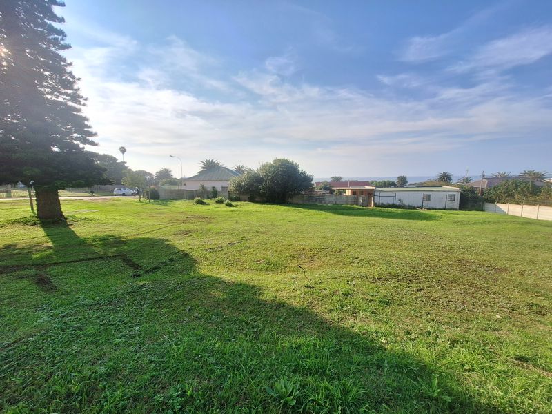 A spacious, level residential vacant land plot featuring established grass, mature trees, and perimeter fencing in a quiet neighborhood setting.