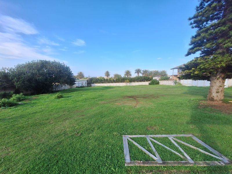 A spacious, level residential plot featuring a well-maintained lawn, mature trees, and secure precast concrete boundary walling.