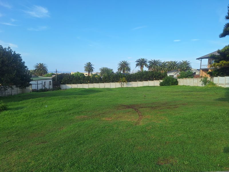 A spacious, level residential plot featuring a well-maintained lawn and secure precast concrete boundary walls.