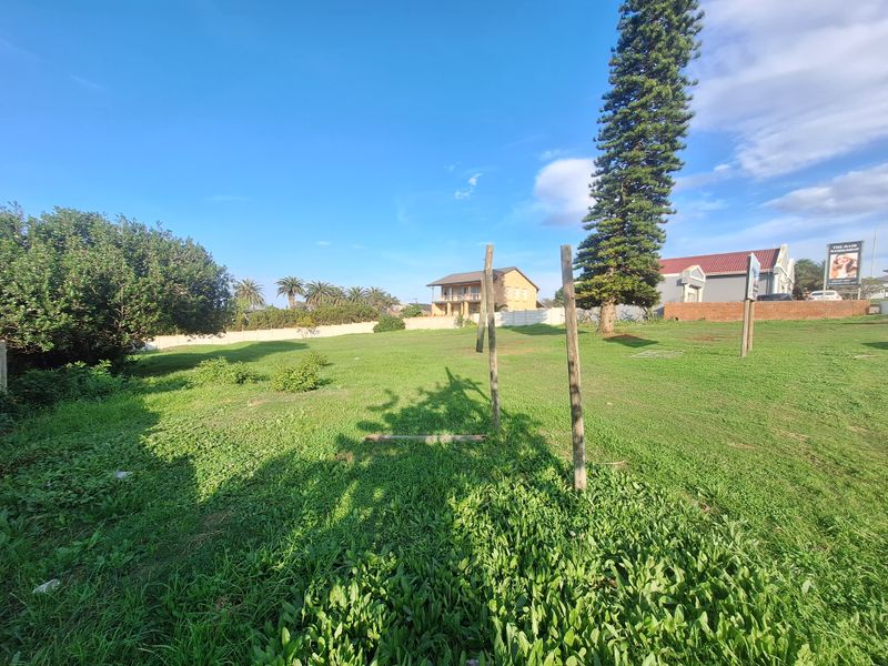 A vacant residential plot featuring established greenery, mature trees, and perimeter walling, offering a clear space for future development.