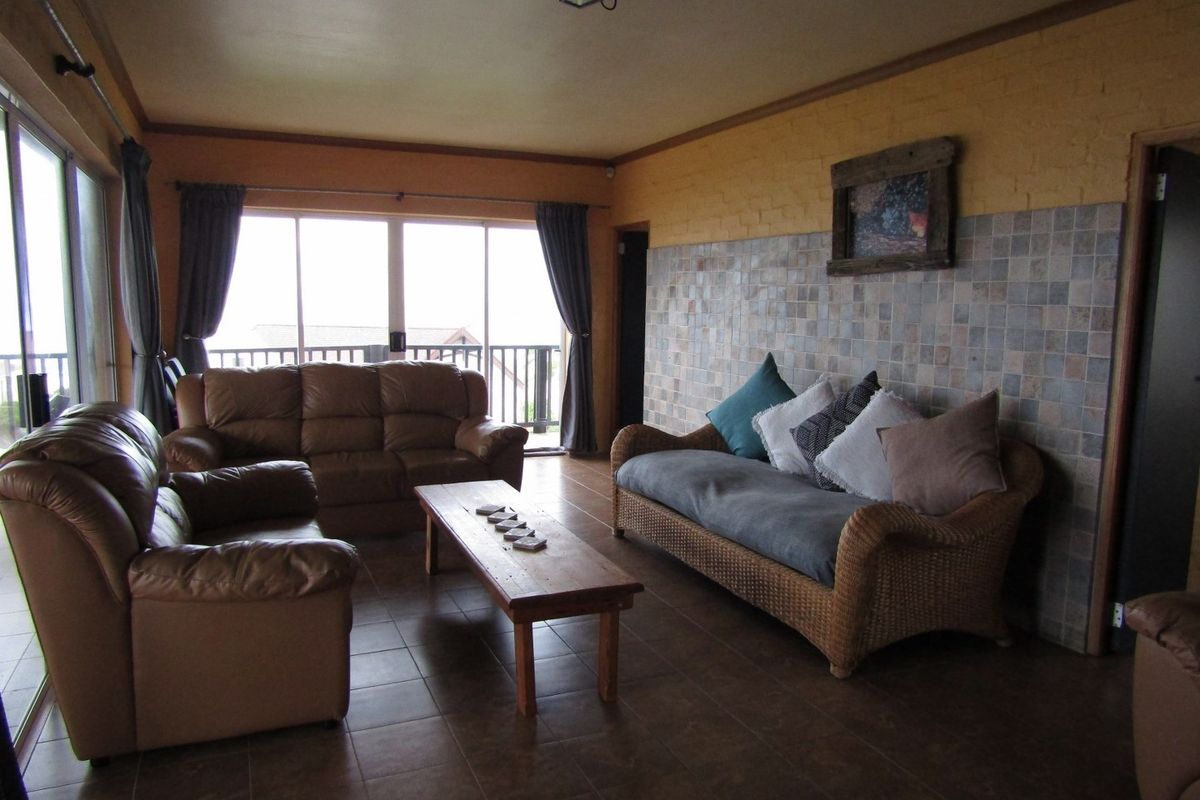 A spacious living room featuring tiled flooring, a tiled feature wall, and large sliding glass doors providing access to an outdoor area.