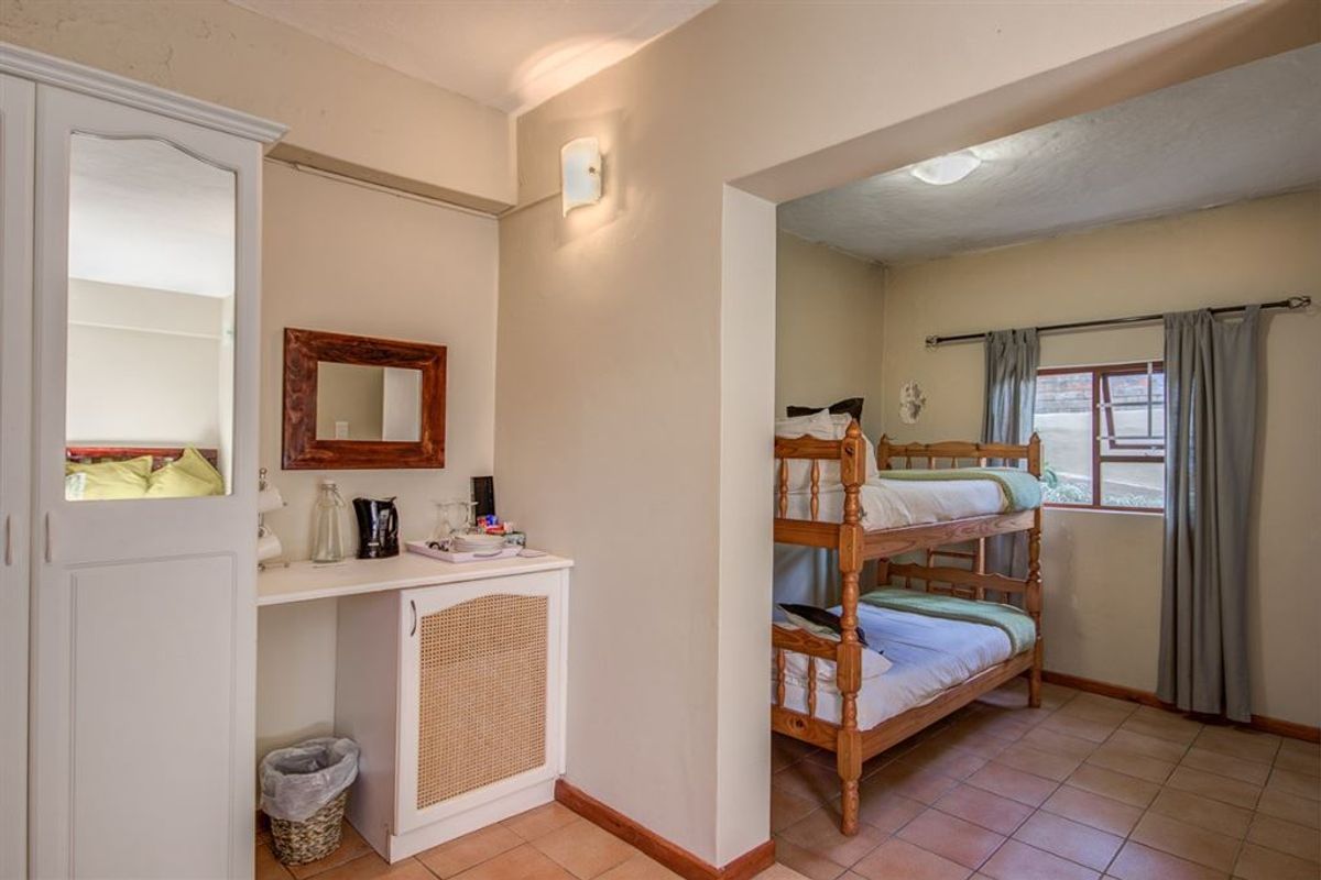 A bedroom featuring tiled flooring, a built-in wardrobe with a mirror, and a partitioned sleeping area.