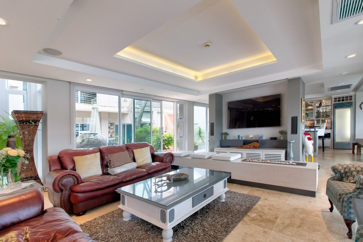 Spacious living room featuring a recessed tray ceiling with cove lighting, stone flooring, and large sliding glass doors leading to an outdoor area.