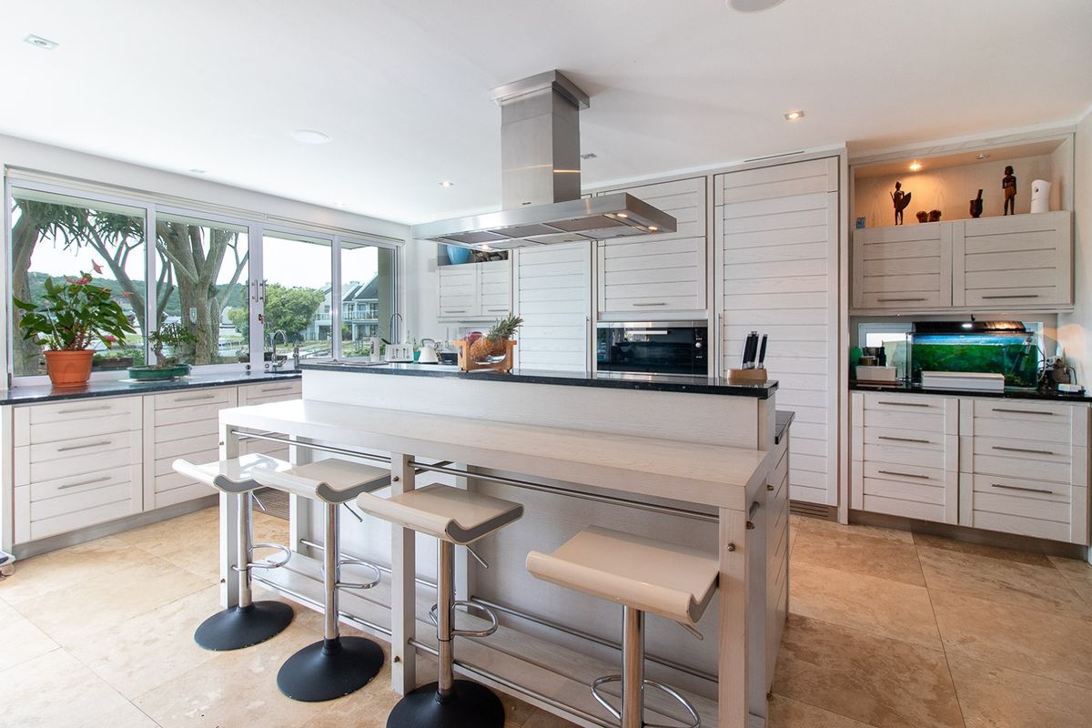 Modern kitchen featuring integrated cabinetry, stone countertops, a central island with breakfast bar, and high-quality stainless steel appliances.