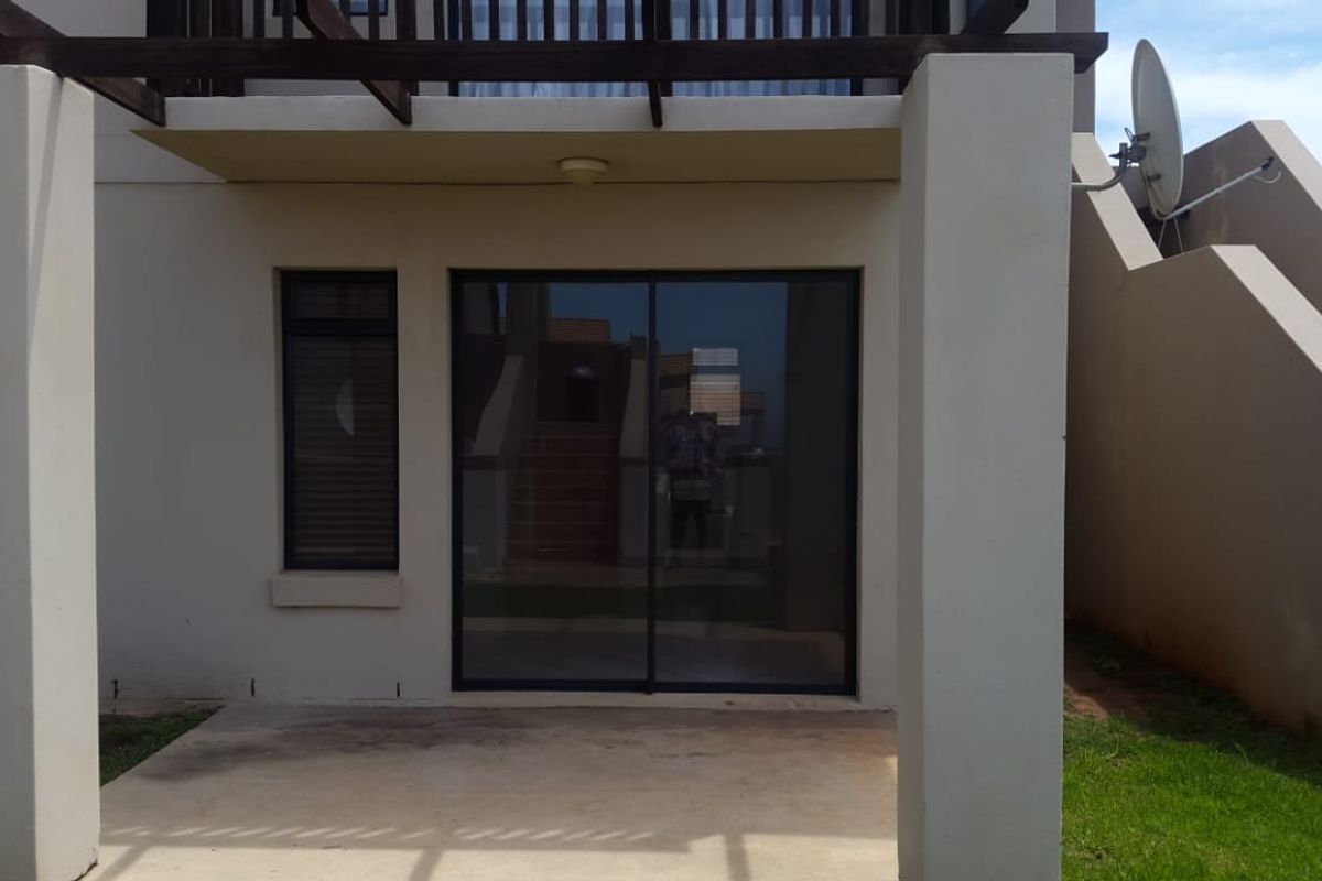 A ground floor patio area featuring a sliding glass door entrance, a timber pergola structure, and exterior lighting.