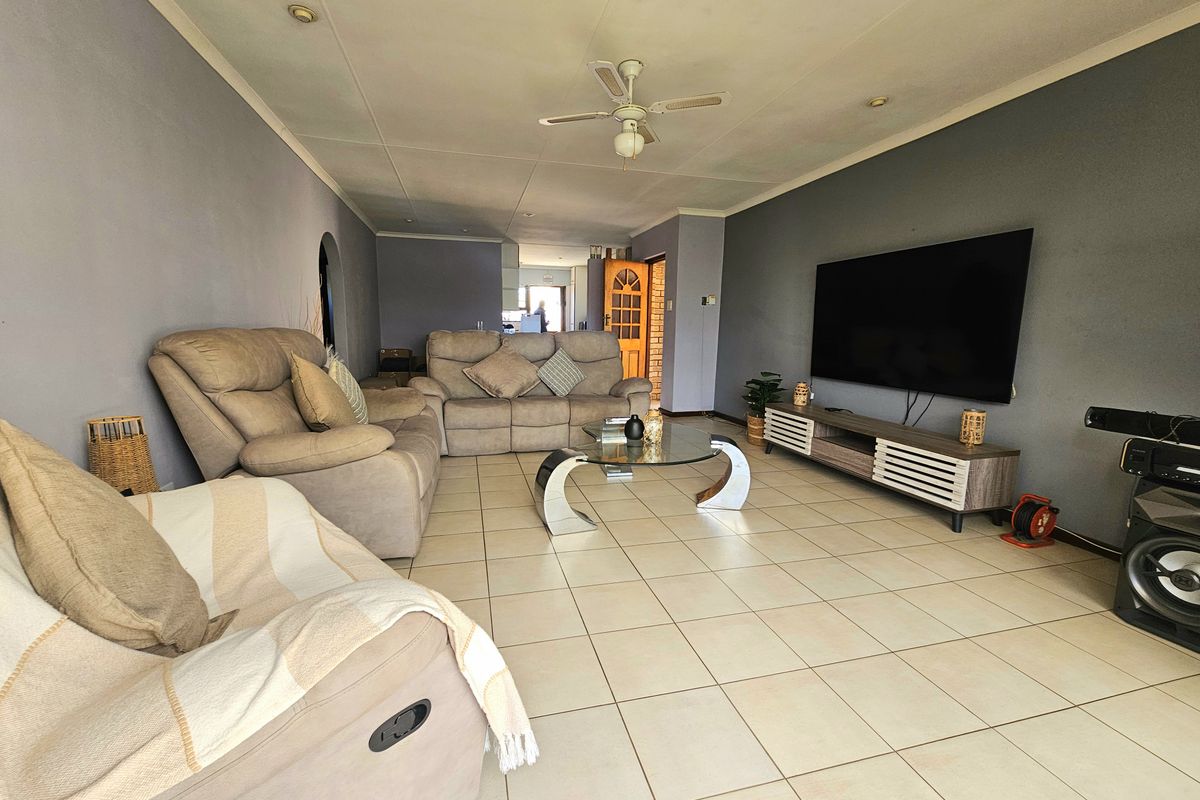 Spacious living room featuring neutral tiled flooring, recessed ceiling lighting, and a central ceiling fan, providing a comfortable and functional family area.
