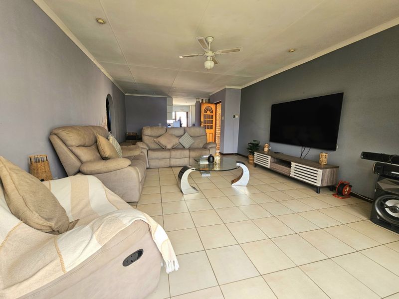 Spacious living room featuring neutral tiled flooring, recessed ceiling lighting, and a central ceiling fan, providing a comfortable and functional family area.