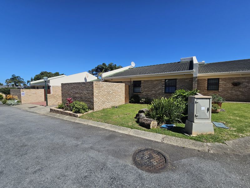 Front exterior view of a single-story brick house featuring a tiled roof, private brick boundary wall, and a small front garden area.