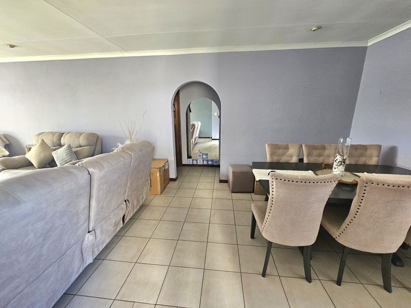 Open plan living and dining area featuring neutral tiled flooring and a distinctive arched doorway leading to adjacent rooms.