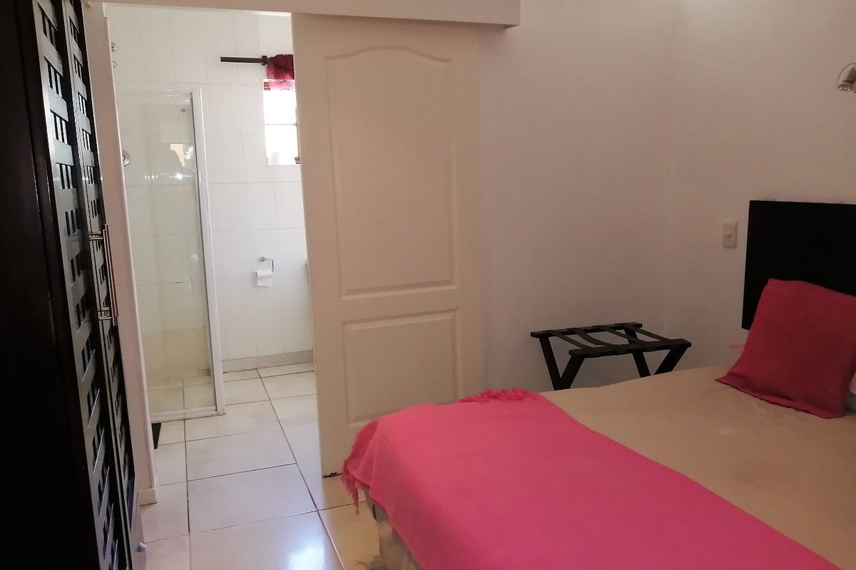 A hotel bedroom featuring tiled flooring, a built-in wardrobe, and an adjoining en-suite bathroom with a shower enclosure.