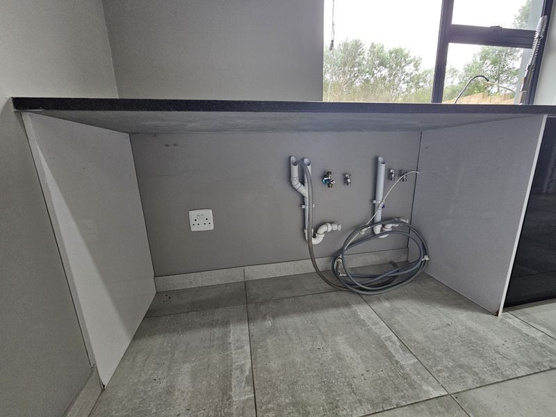 A dedicated laundry or utility space featuring a stone countertop, tiled flooring, and pre-installed plumbing connections for appliances.