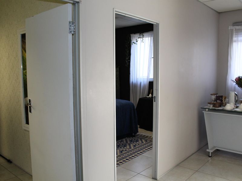 An office interior featuring tiled flooring and a doorway leading to an adjacent room with natural light.