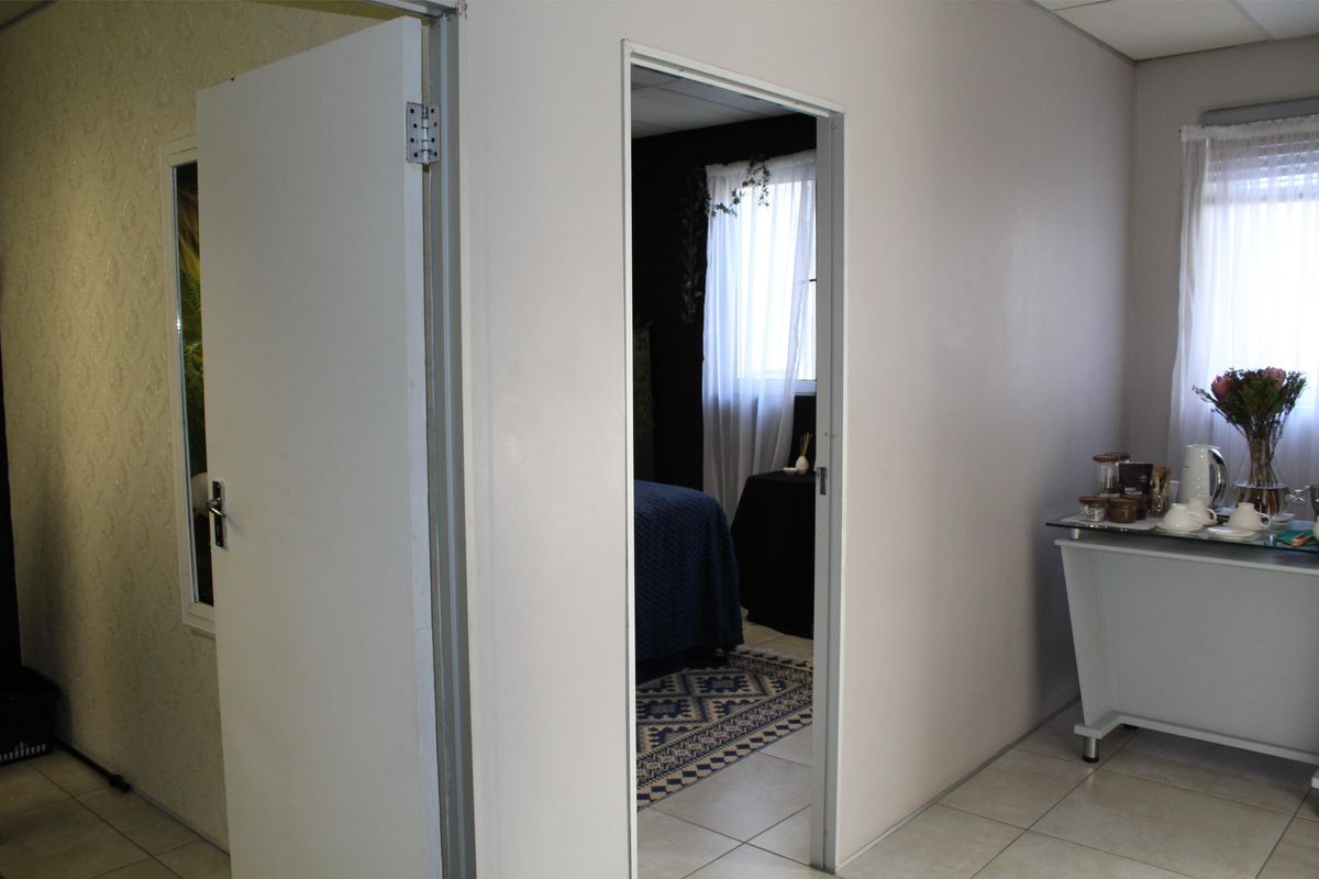 An office interior featuring tiled flooring and a doorway leading to an adjacent room with natural light.