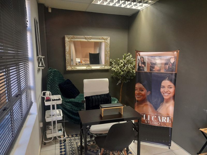 A compact office space featuring a drop ceiling with integrated lighting and venetian blinds, currently utilized as a professional studio.