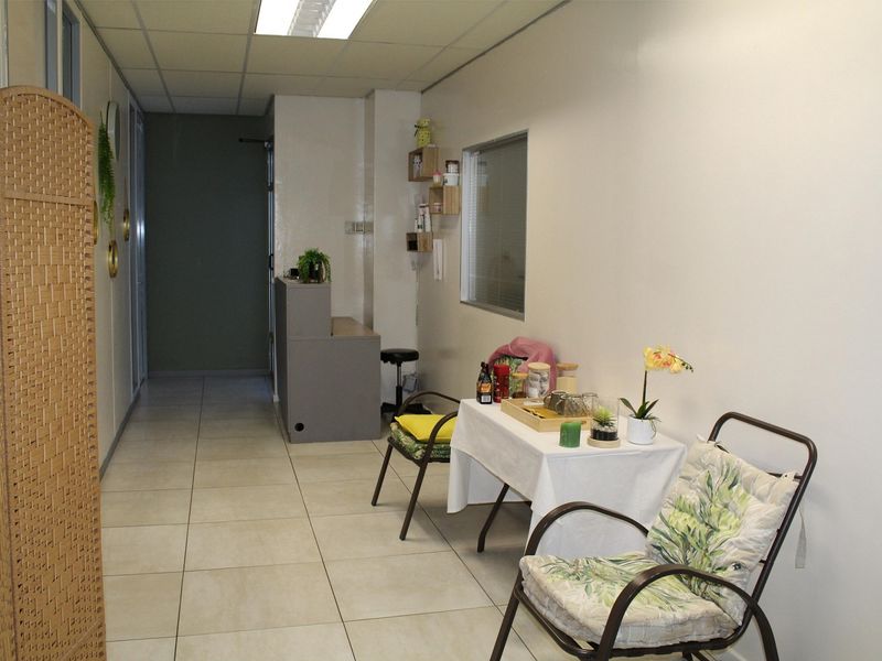 A functional office space featuring tiled flooring, a built-in reception desk, and a suspended ceiling with integrated lighting.