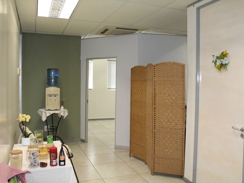 A functional office space featuring tiled flooring, a suspended ceiling with recessed lighting, and integrated air conditioning, providing a clean and professional work environment.