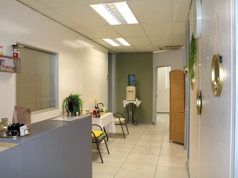 A functional office reception area featuring tiled flooring, recessed fluorescent lighting, and a built-in reception desk.
