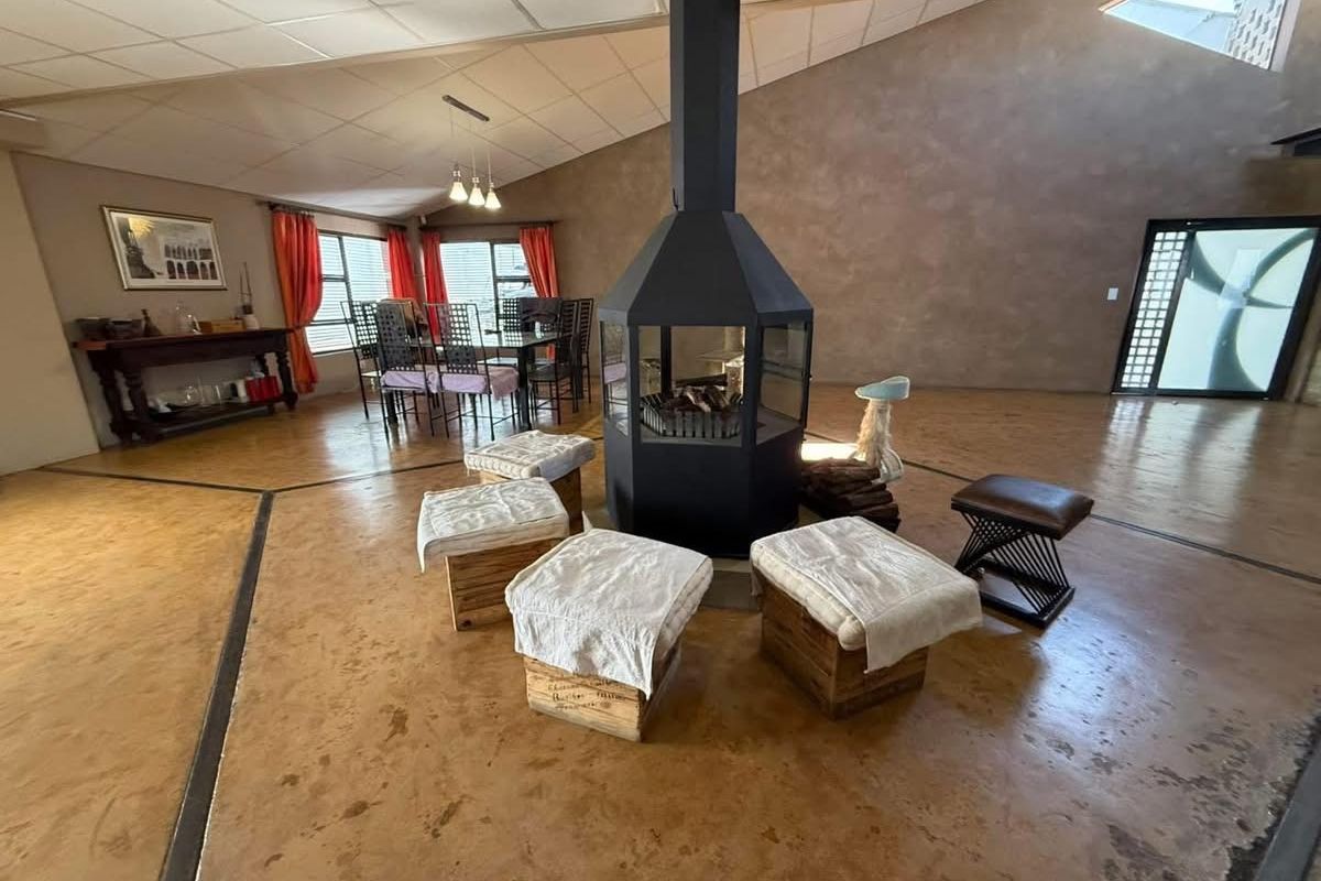 Spacious living area featuring a central freestanding fireplace, polished concrete floors, and high ceilings with integrated lighting.