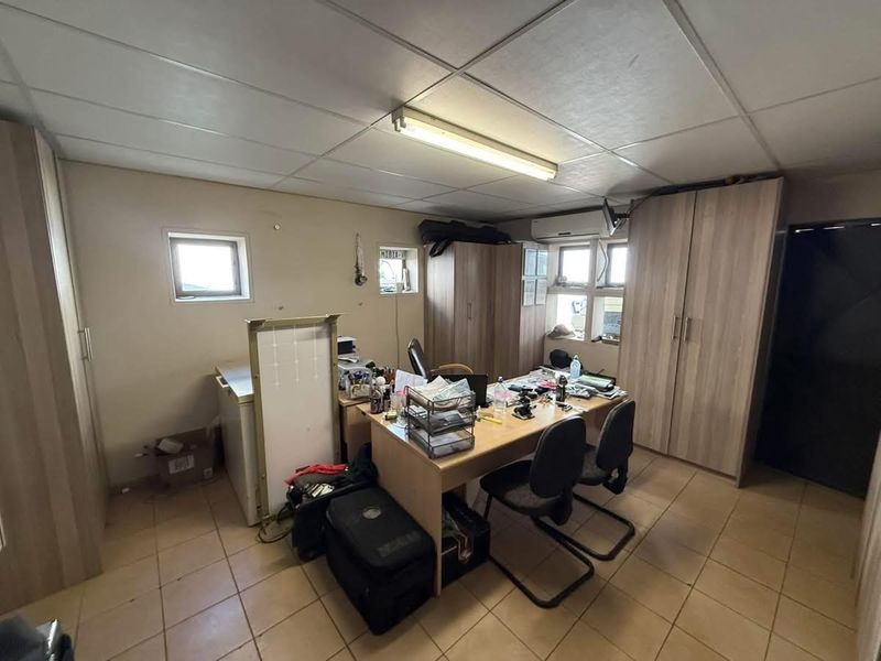 Functional office space featuring tiled flooring, built-in storage cupboards, suspended ceiling, and a wall-mounted air conditioning unit.