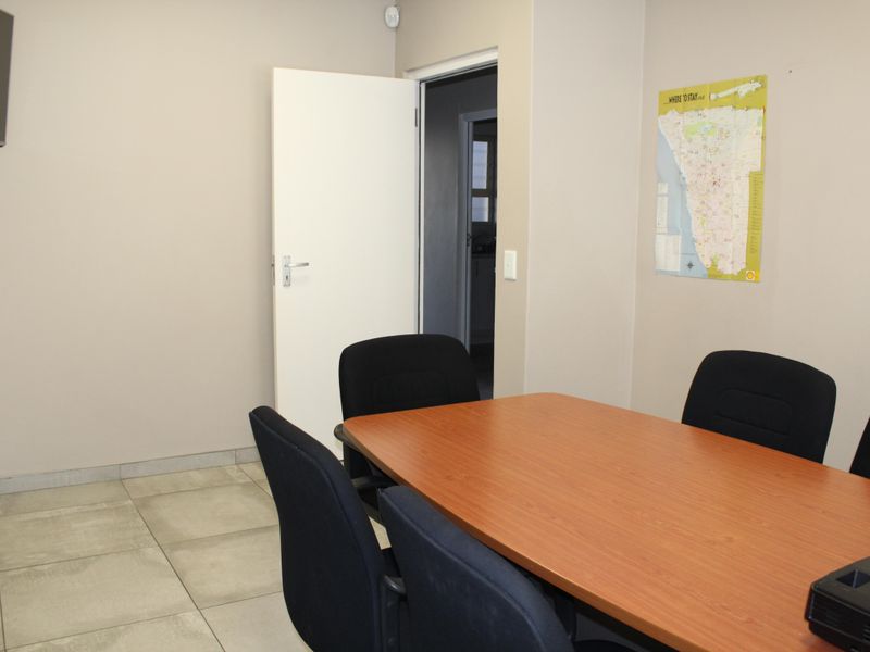 A functional office space featuring neutral wall tones and durable tiled flooring, suitable for a professional meeting or workspace environment.