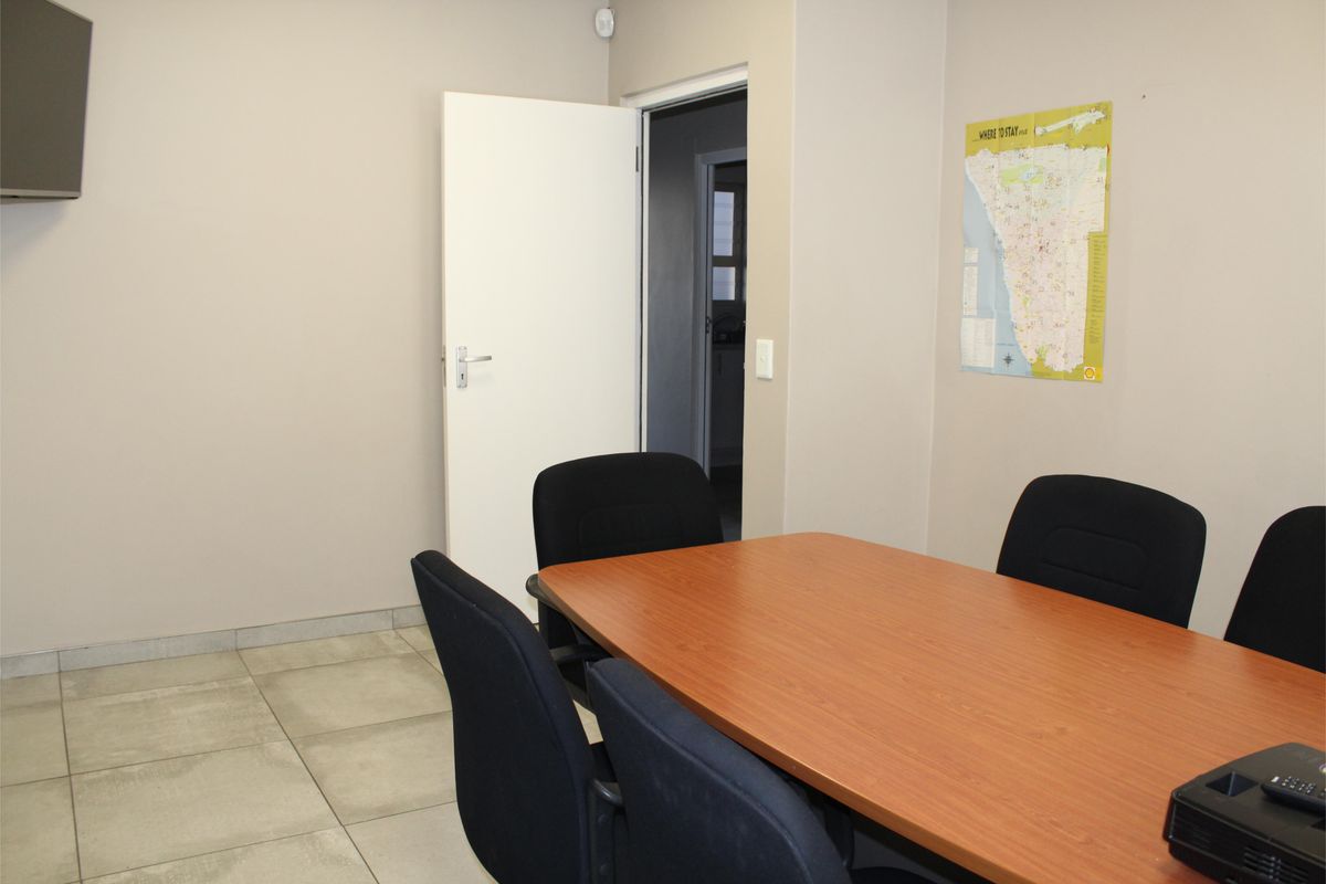 A functional office space featuring neutral wall tones and durable tiled flooring, suitable for a professional meeting or workspace environment.