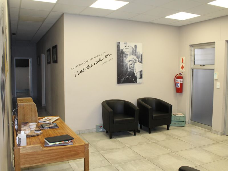 A professional office reception area featuring tiled flooring, recessed lighting, and a glass-panelled entrance door.