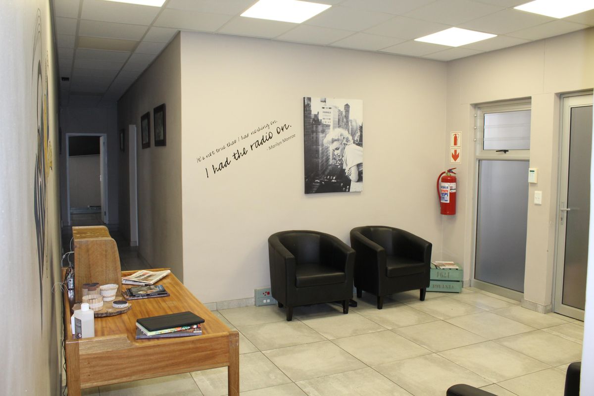 A professional office reception area featuring tiled flooring, recessed lighting, and a glass-panelled entrance door.