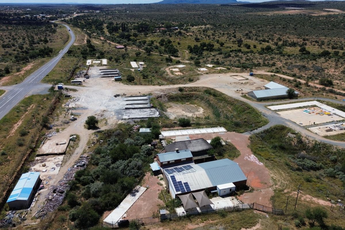 Aerial view of an industrial property featuring multiple structures, solar panel installations, and extensive surrounding land with direct road access.