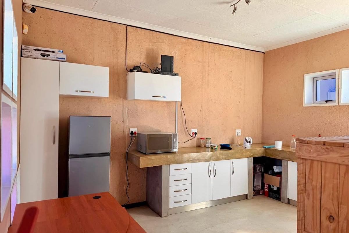 A functional kitchen area featuring built-in cabinetry, concrete countertops, and wall-mounted storage units in an industrial-style setting.