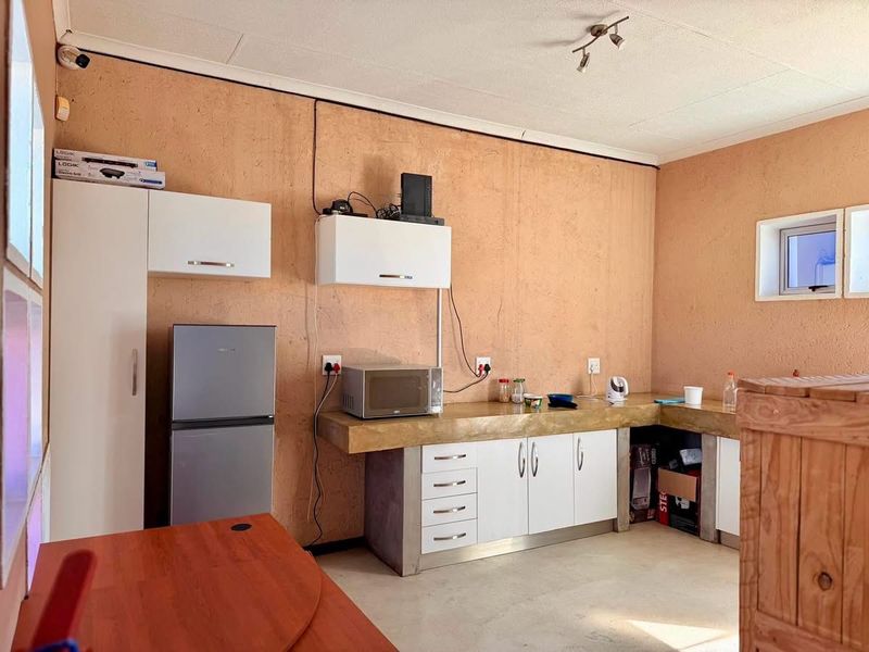 A functional kitchen area featuring built-in cabinetry, concrete countertops, and wall-mounted storage units in an industrial-style setting.